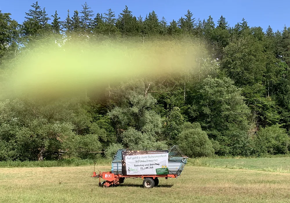 Gesangverein Dankoltsweiler: Bauzaunbanner an Traktoranhänger befestigt, steht auf Feld mit blauem Himmel
